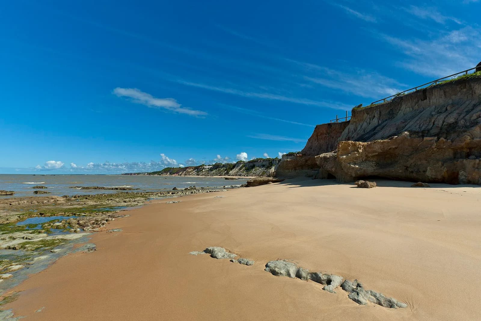 Praia deserta em Cumuruxatiba com as falésias ocre da Costa das Baleias ao fundo