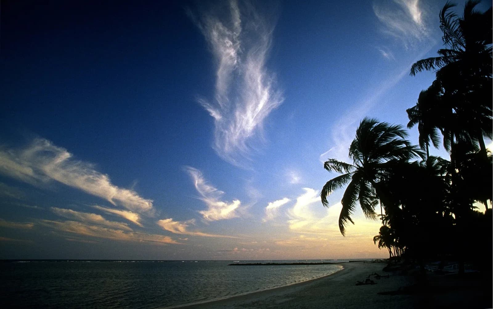 Entardecer na Ilha de Itaparica, com o mar sem onda da Baía de Todos os Santos e coqueiros na orla
